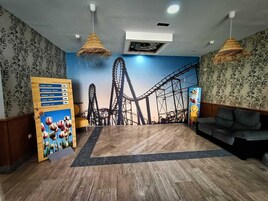 Una habitación con un mural de montañas rusas, un letrero de bufé, un sofá y piso de madera.