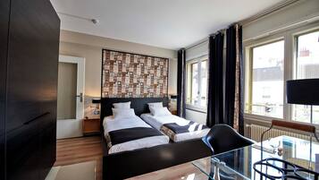 Een moderne hotelkamer met een groot bed, een glazen tafel en uitzicht op de stad.