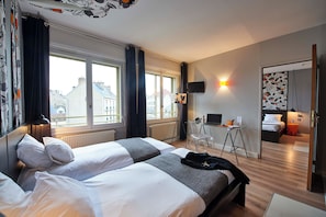 Habitación de hotel con dos camas, un escritorio, una silla, una computadora y vistas a la ciudad.