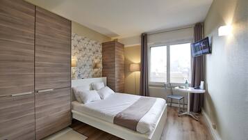 A modern hotel room with a bed, a desk, and a TV.