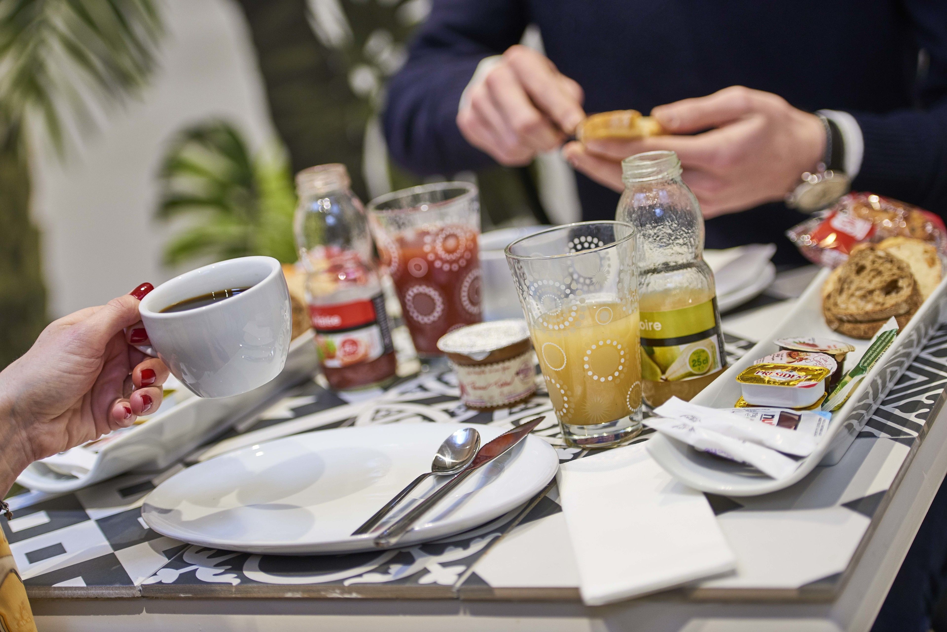 Een ontbijtsetting met een tafel gedekt voor twee personen, inclusief borden, bestek, glazen en diverse soorten eten.