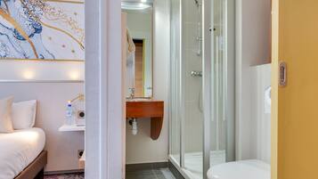 A modern bathroom with a glass shower enclosure, a white toilet, and a wooden vanity.
