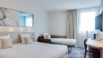 Une chambre d’hôtel avec deux lits, un bureau, une chaise, un grand miroir et une fenêtre avec des rideaux.
