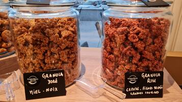 Två glasburkar märkta med "Granola Doré" och "Granola Rose" står på en träbänk.