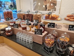 Una vitrina de pastelería con distintos frascos de rellenos, pasteles y productos de repostería.