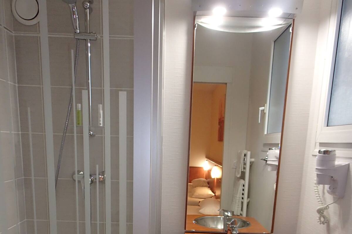 Une salle de bain avec une douche à parois de verre, un meuble-lavabo en bois et un miroir.