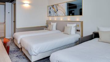 A hotel room with two beds, a large mirror, and a wall-mounted artwork.