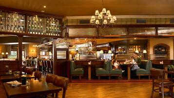 A bar area with wooden furniture, a bar counter, and shelves of liquor bottles.