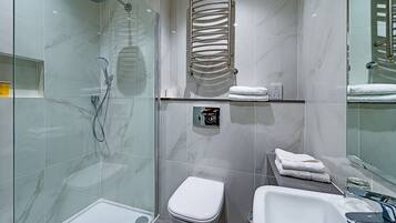 A modern bathroom with a glass shower enclosure, a toilet, and a sink with a mirror.