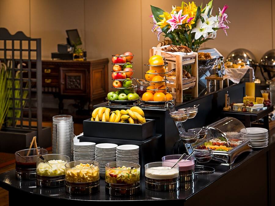 A buffet with various food items and a decorative flower arrangement.