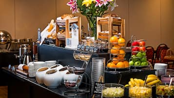 A buffet with various food items, including fruits, pastries, and condiments.