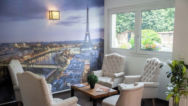 A room with a large mural of the Eiffel Tower, a window with a view of greenery, and a seating area with a table and chairs.