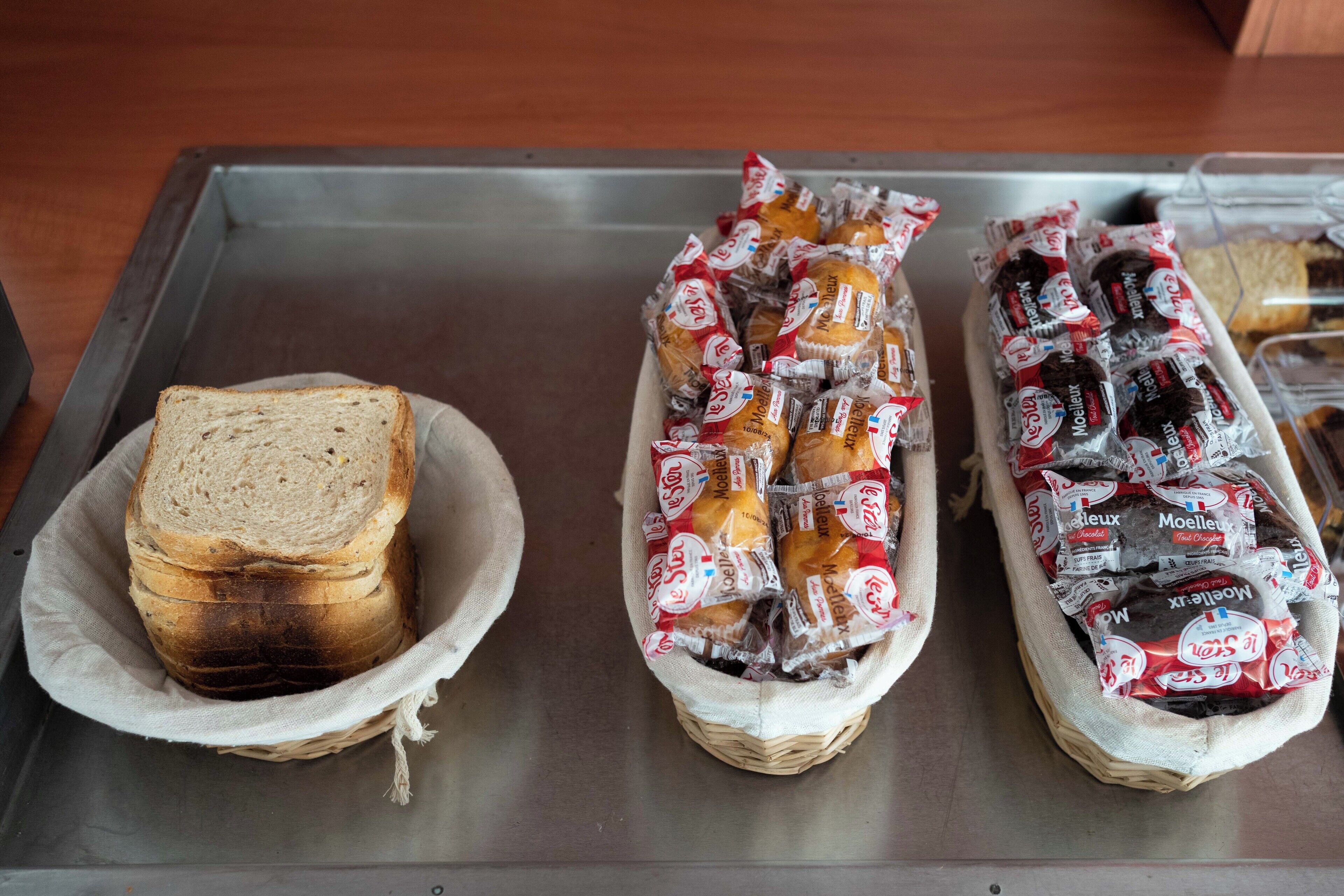 A tray with three bread baskets, one with sliced bread and two with packaged bread.