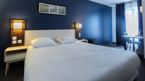 A hotel room with a large bed, bedside tables, a desk, and a chair.