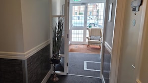 A hotel entrance with a potted plant, a striped armchair, and a sign indicating the 'Claudius Suite'. - The Woolpack Inn (Chichester)