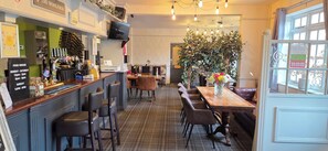 Un interior de restaurante con barra, mesas y un ventanal grande.