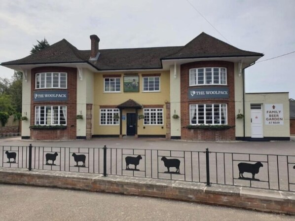 A two-story building with 'The Woolpack' signage on both the ground and upper floors.