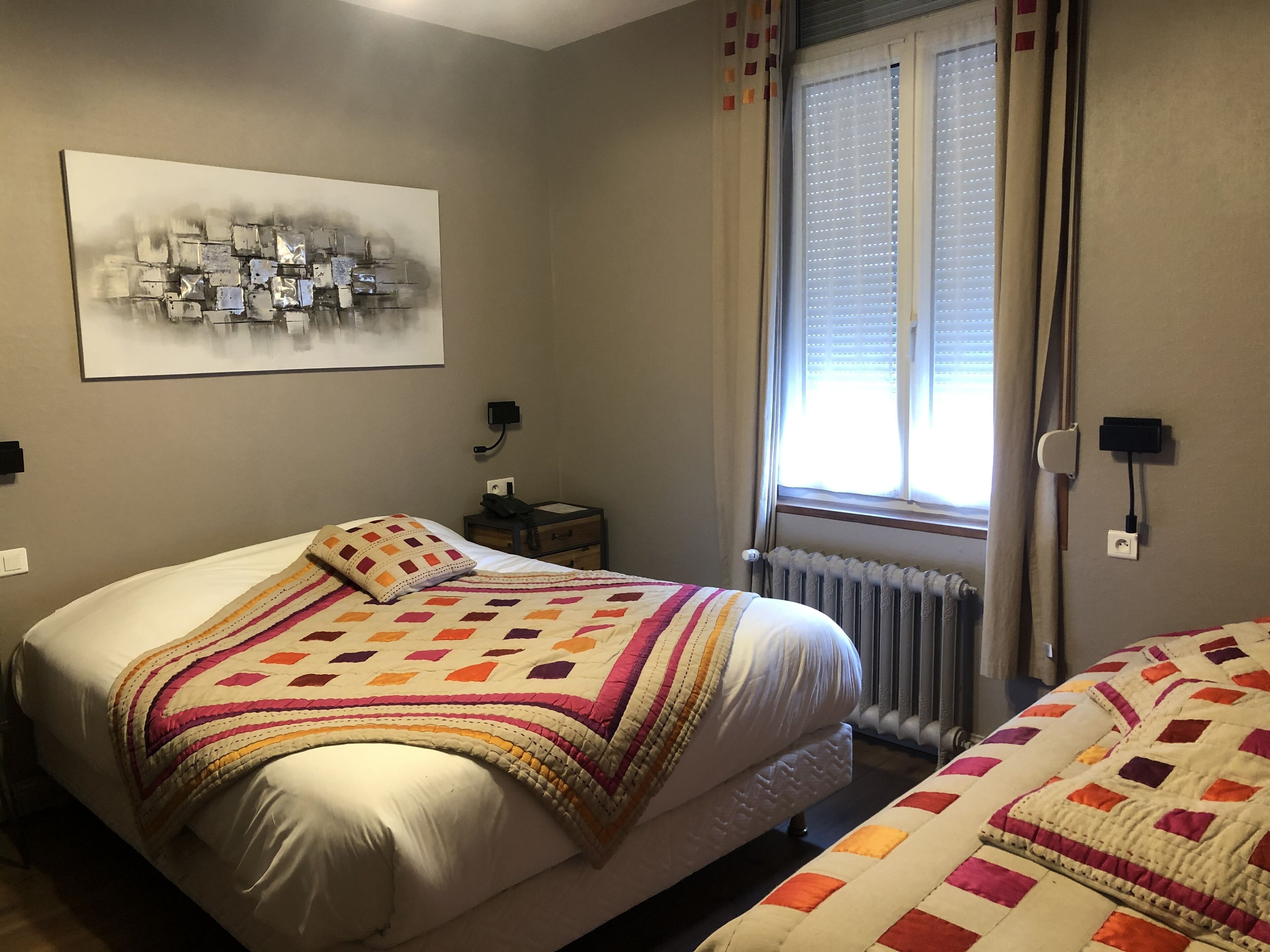 Ein Schlafzimmer mit einem großen Bett, einem Nachttisch, einer Fenster mit Jalousien und einer Wandsteckdose.