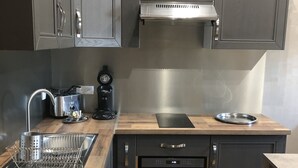 Una cocina moderna con armarios oscuros, una campana extractora de acero inoxidable, un horno empotrado y una encimera de madera.