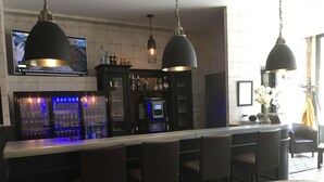 Zona de bar con barra, taburetes y una televisión mostrando un noticiero.