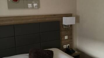 Ein Hotelzimmer mit einem Bett, einem Nachttisch, einer Lampe und einem Wandbild.