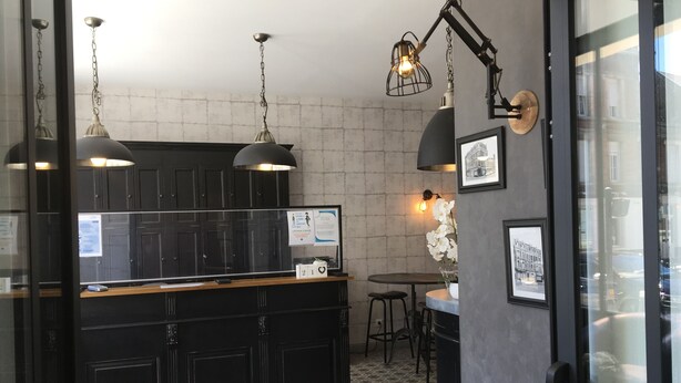 Cocina moderna con armarios negros, encimera de madera e iluminación colgante. Cuenta con un pequeño comedor con mesa y sillas.