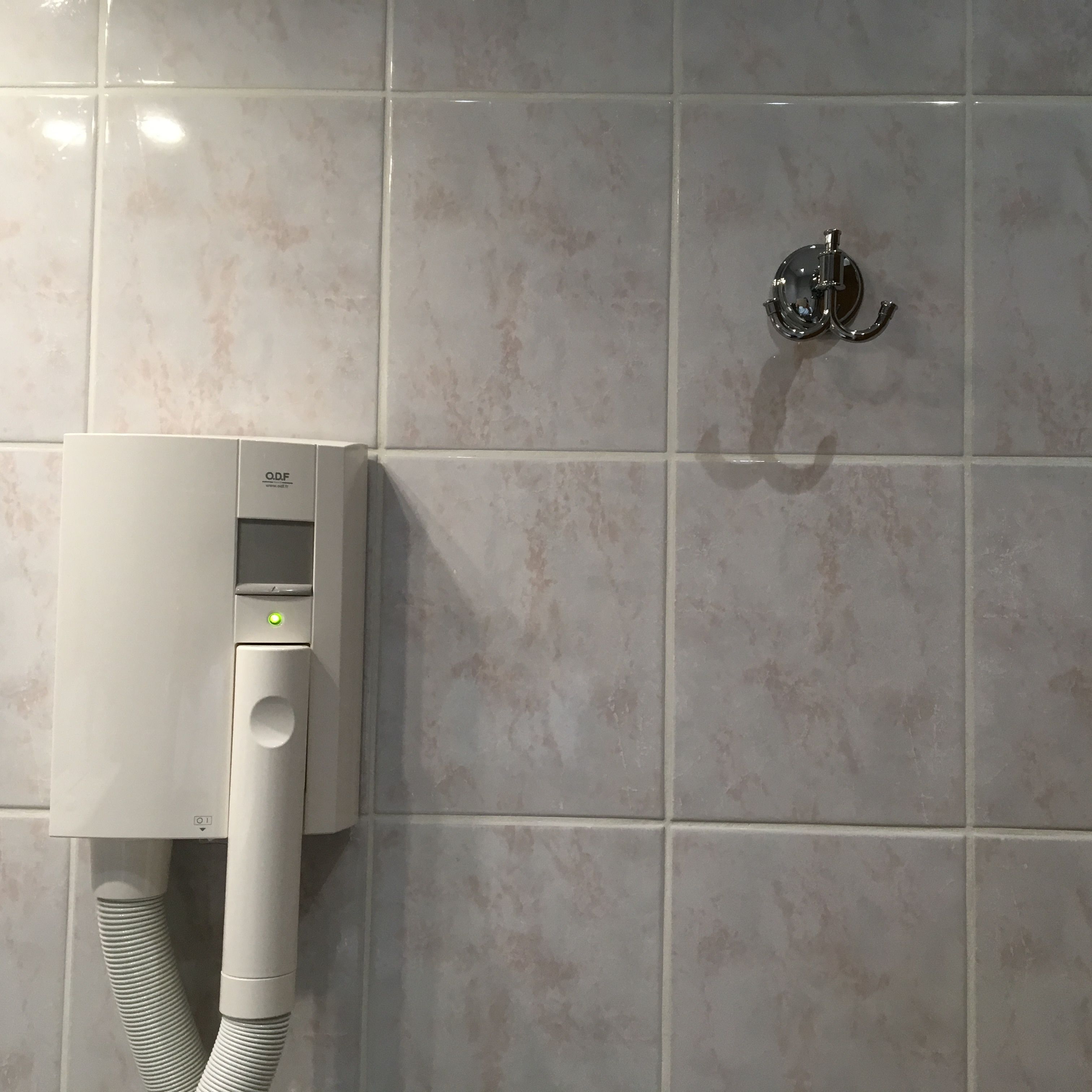 Un bany modern amb comandaments de dutxa fixats a la paret i plat de dutxa manual.
