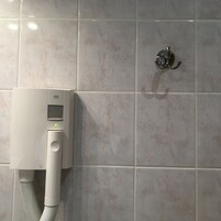 Ein modernes Badezimmer mit einer an der Wand montierten Duschsteuerung und einer Handbrause.