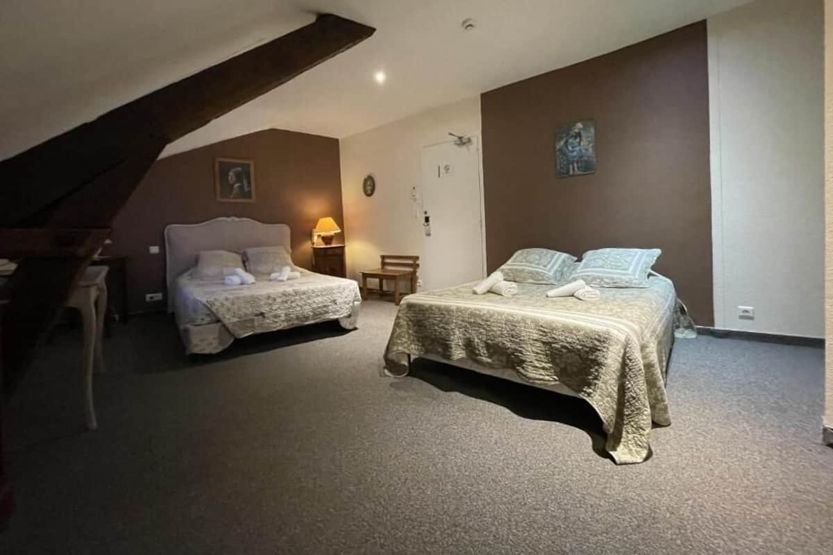A bedroom with two beds, a desk, a chair, a lamp, and a clock on the wall.