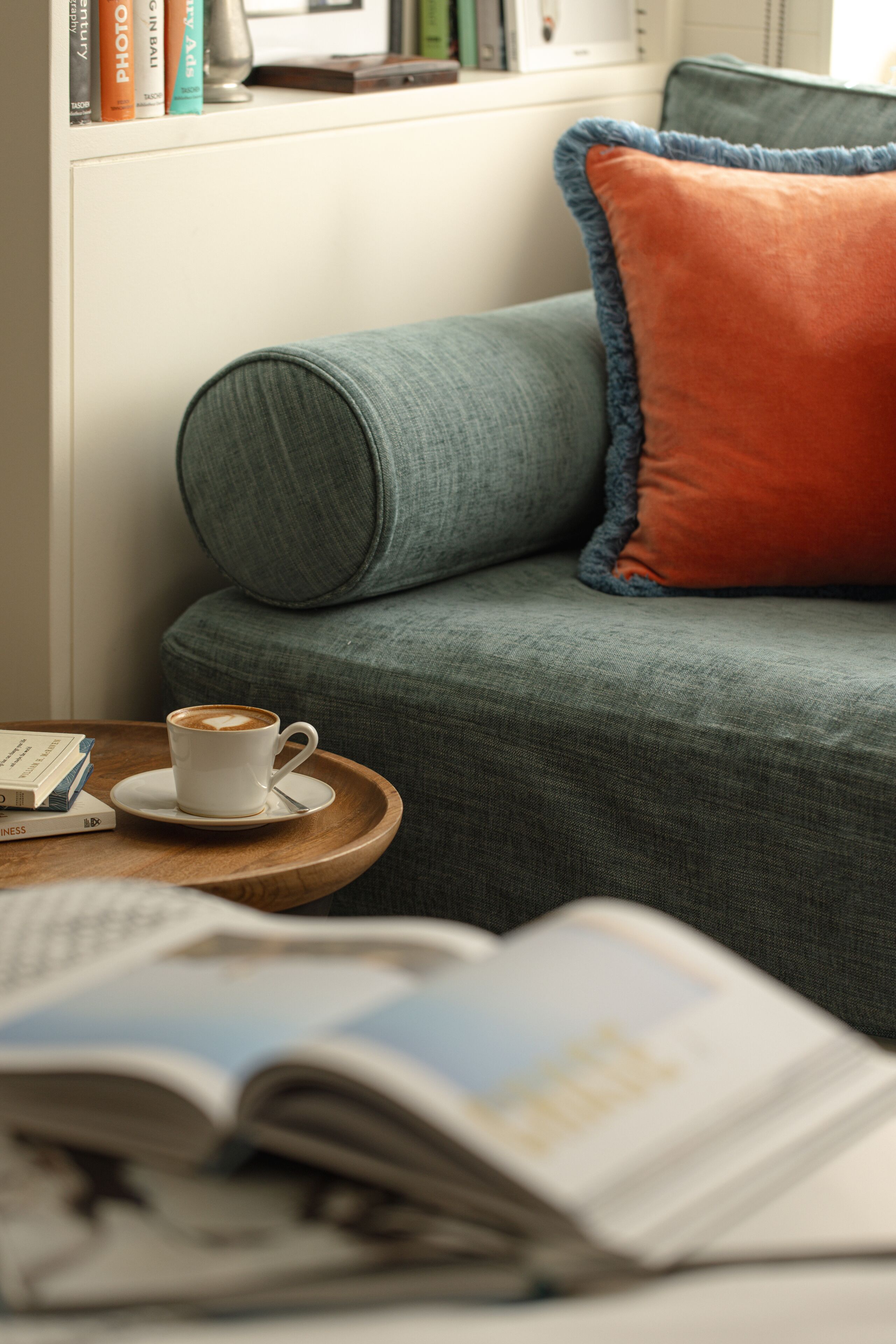 Un rincón acogedor para leer, con un sofá verde, una taza de café sobre una bandeja y un libro en la mesa.