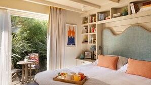 Un dormitorio con cama, mesita de noche y ventana con cortinas.
