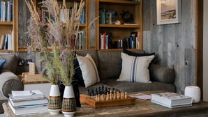 Una sala de estar acogedora con una mesa de centro de madera, un tablero de ajedrez y una estantería llena de libros.