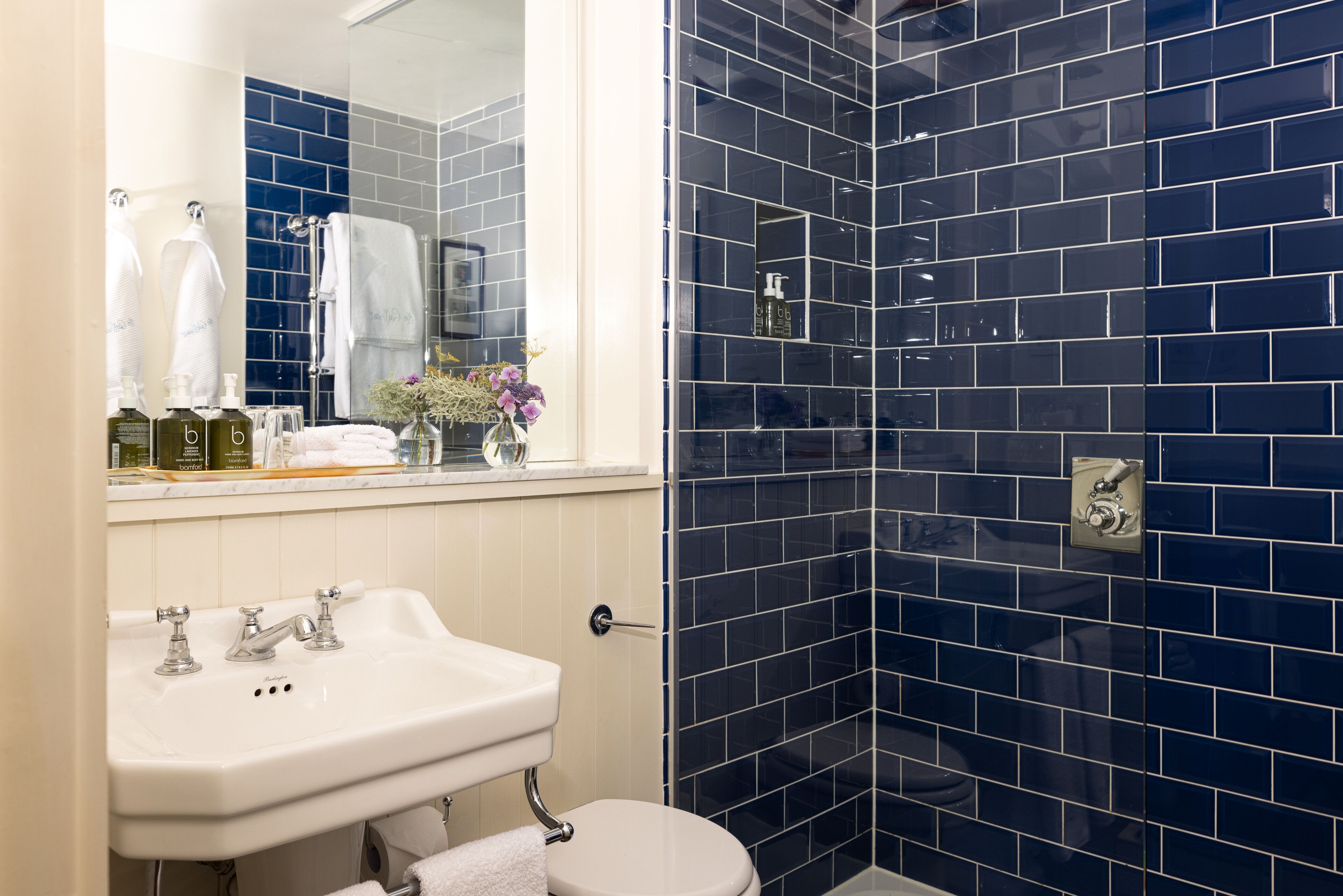 A bathroom with a white sink, a toilet, and a shower area with dark blue tiles.