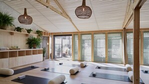 Un estudio de yoga con pisos de madera, tapetes de yoga negros y vigas de madera en el techo.