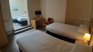 Une chambre d’hôtel avec deux lits, un bureau, une chaise, une télévision et une lampe.