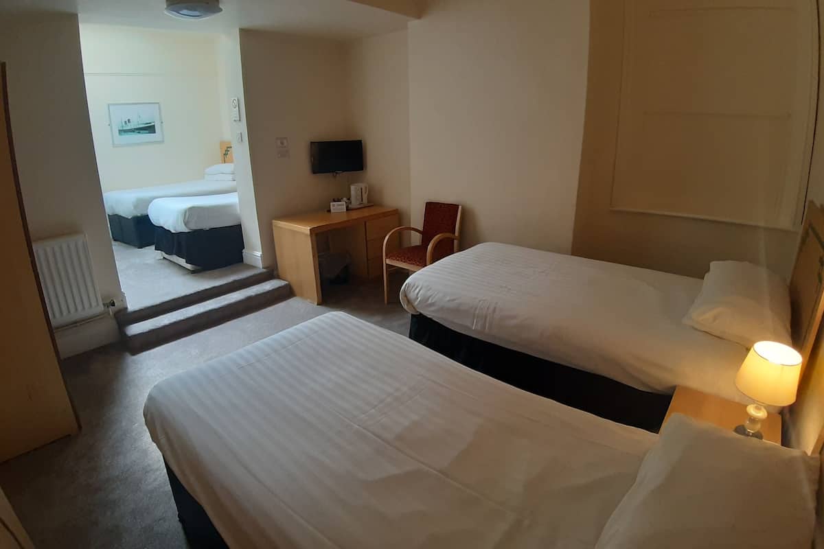 Et hotelværelse med to senge, et skrivebord, en stol, et fjernsyn og en lampe.