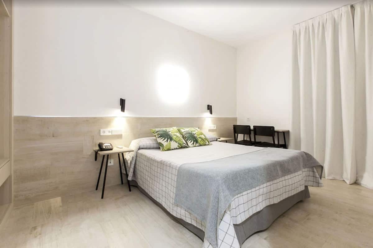 A modern bedroom with a large bed, bedside tables, a desk, and a chair.
