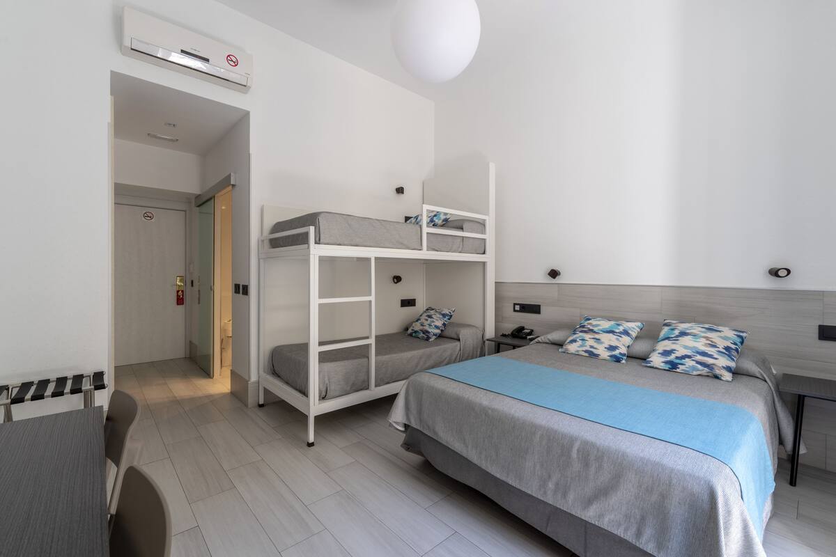 A modern hotel room with bunk beds, a desk, and a chair.