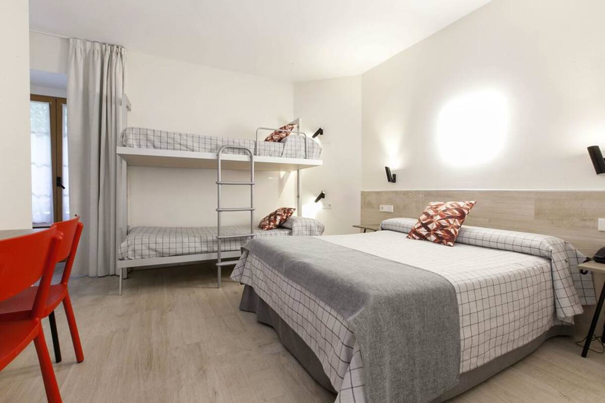 A hotel room with bunk beds, a desk, and a chair.