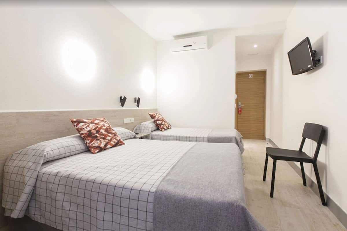 A hotel room with two beds, a flat-screen TV mounted on the wall, and a chair.