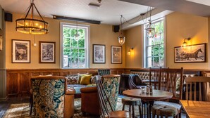 A cozy interior with a wooden bench, cushioned seating, and a round table with chairs.
