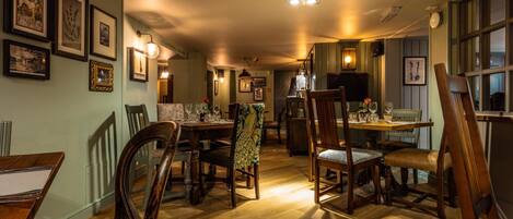 A dining area with wooden furniture, framed pictures on the walls, and a patterned rug.