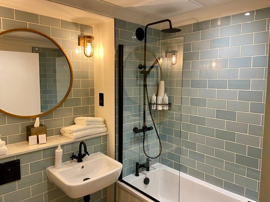 A bathroom with a sink, mirror, and shower.