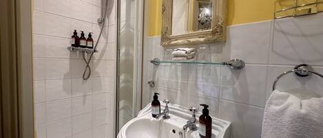 A modern bathroom with a glass shower enclosure, a white sink with dual faucets, and a mirror above the sink.