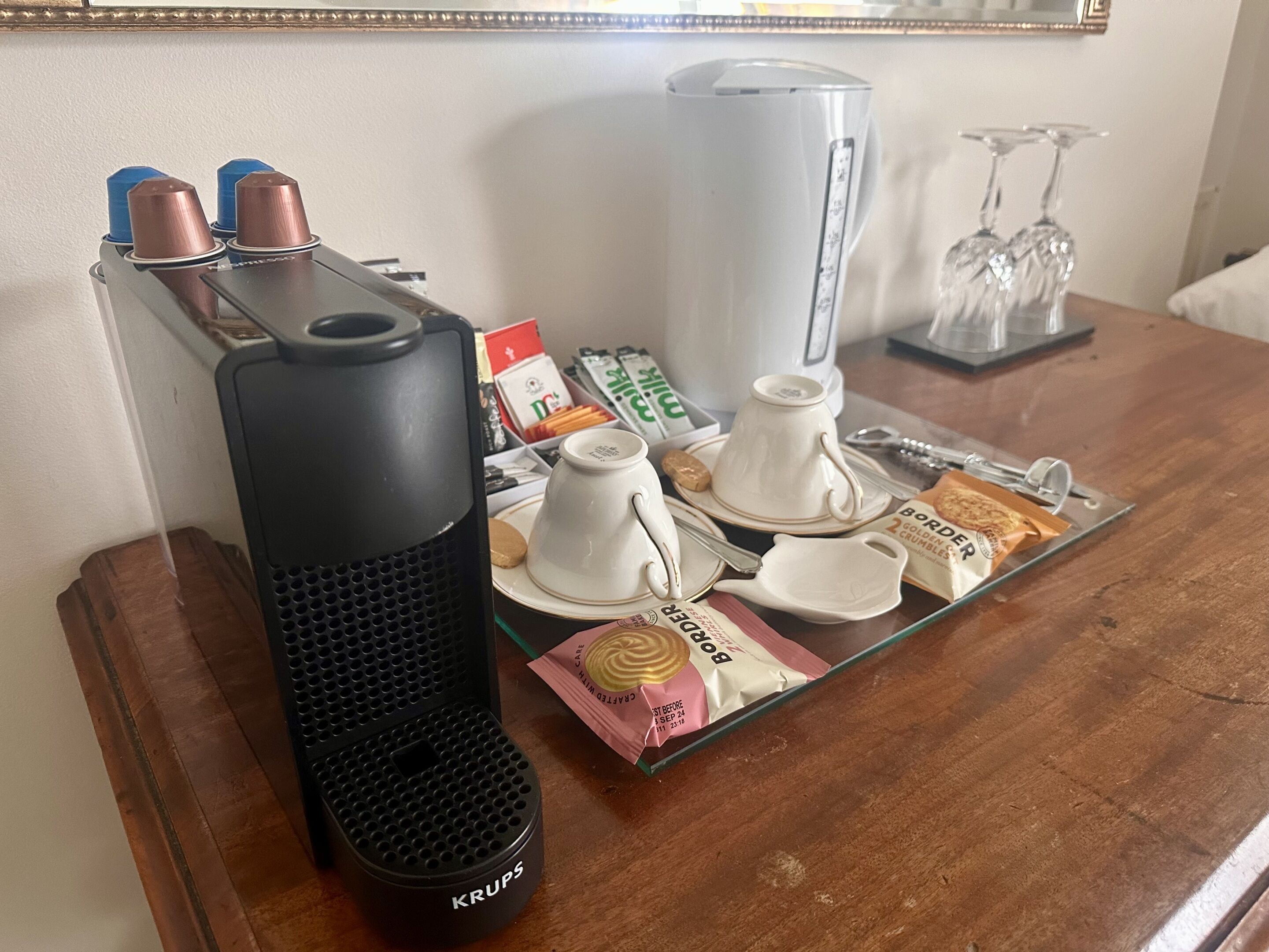 Una mesa con cafetera, tazas, tetera y algunos alimentos.