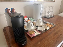 Una mesa con cafetera, tazas, tetera y algunos alimentos.