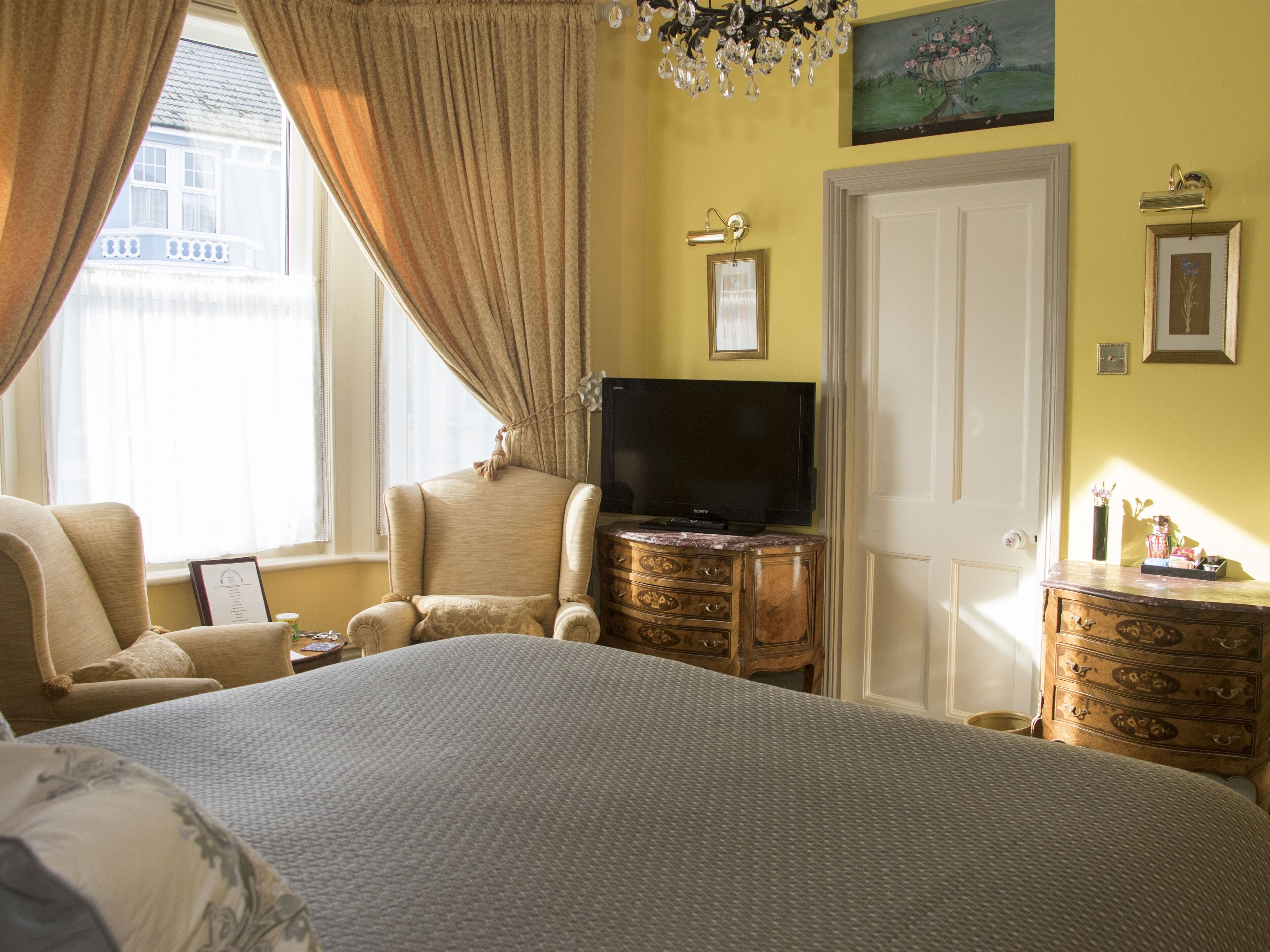A bedroom with a large bed, a television, a dresser, and a chair.