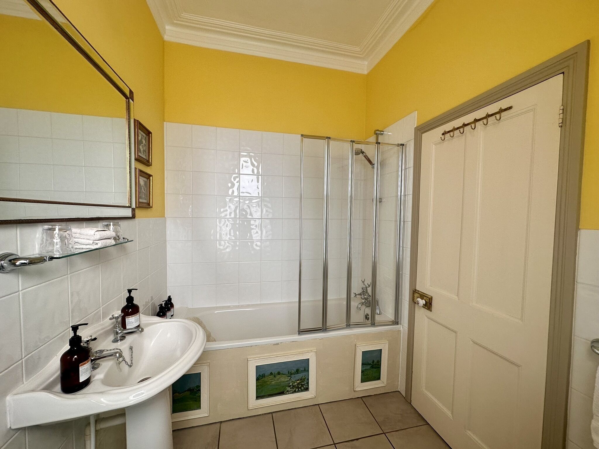 Un baño con lavamanos blanco, cabina de ducha de vidrio y puerta blanca.