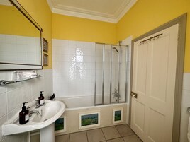 Un baño con lavamanos blanco, cabina de ducha de vidrio y puerta blanca.