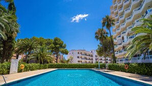 Una piscina rodeada de palmeras y un edificio de varios pisos.